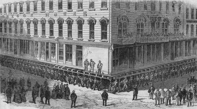 Engraving of men working jackscrews under a large brick hotel to raise it