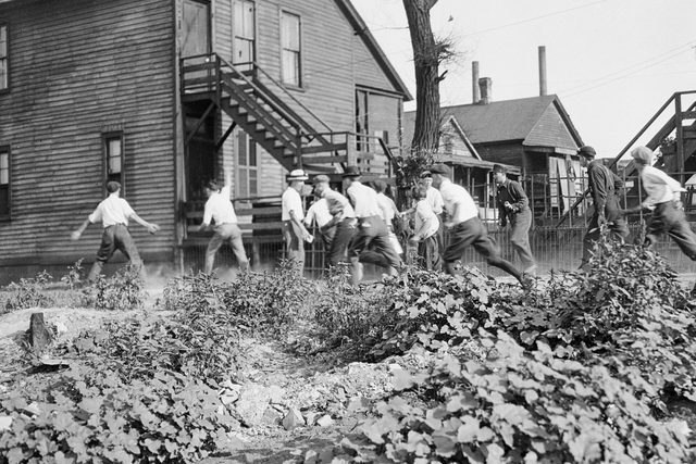 Photograph of men running down a street of frame houses during the 1919 riot
